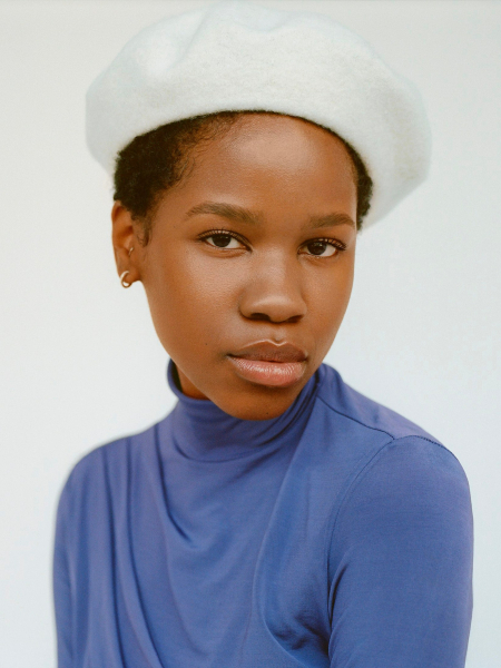 portrait of a person wearing a periwinkle turtleneck and white beret